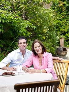 男人和女人坐在花园的桌子旁白天高清图片素材