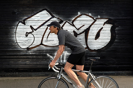 在街上路过涂鸦的男自行车手背景图片