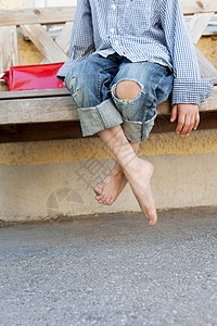 男孩光着脚坐在长凳上图片