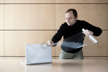 男人用塑料薄膜包装电脑图片