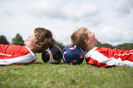 足球游戏两个男孩头枕着球休息背景