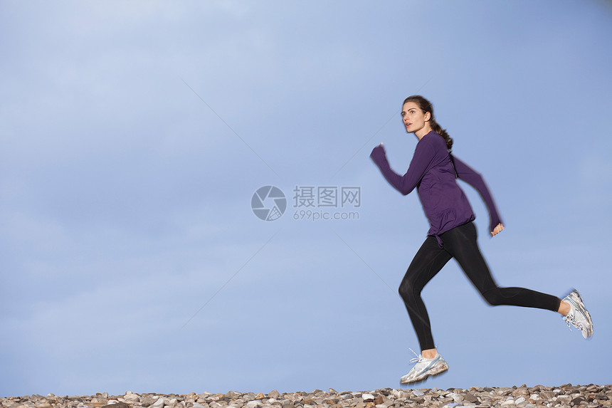 沿着鹅卵石滩慢跑的女人图片