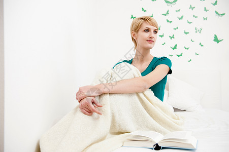 女人裹着毯子坐在床上图片
