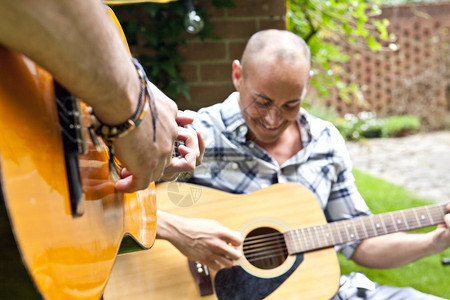 两位男性朋友在花园里弹吉他的短镜头背景图片