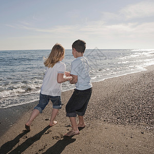 男孩和女孩在海滩上奔跑图片