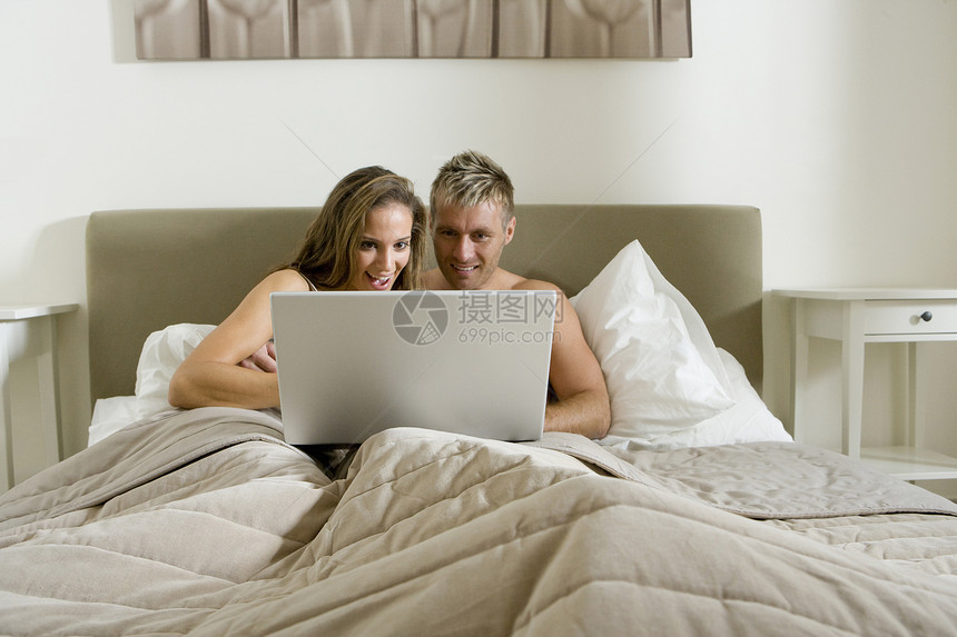 年轻夫妇在床上使用笔记本电脑图片