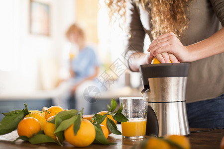 水果搅拌机小女孩在厨房里榨橘子汁背景