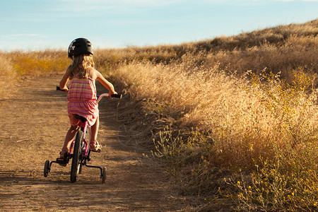 女孩骑自行车草地高清图片素材