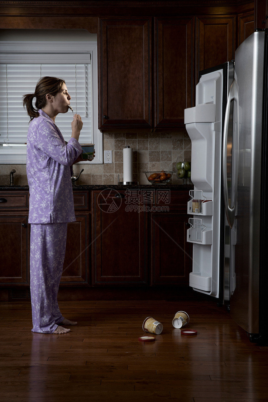 穿睡衣的女人在冰箱前吃冰淇淋图片
