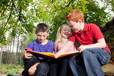 三个孩子一起看一本书背景图片