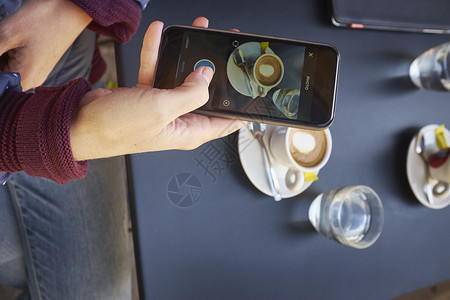 俯视街边咖啡厅智能手机上中年女性使用手机图片
