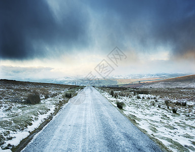 英国约克郡斯韦莱德尔，前方有暴风云的结冰乡村道路背景图片