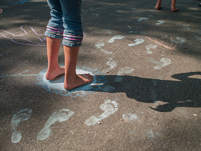 女孩赤脚在人行道上踩粉笔脚印图片