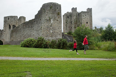 父亲和女儿在爱尔兰米斯郡的特里姆城堡跑步图片