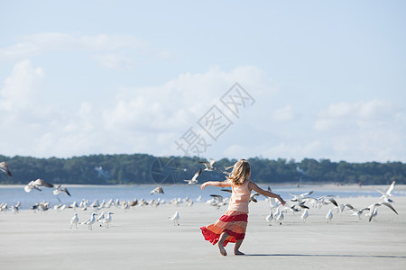 在海鸥中间的海滩上奔跑的女孩童年高清图片素材