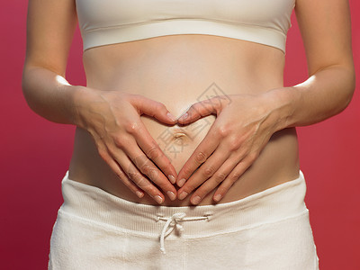 抠肚脐在腹部比心的孕妇背景
