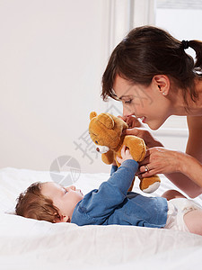 妈妈和宝宝玩泰迪熊卧室高清图片素材
