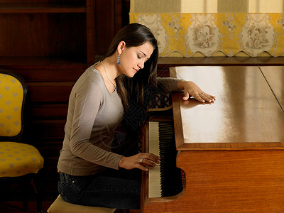 年轻女子单手弹钢琴图片