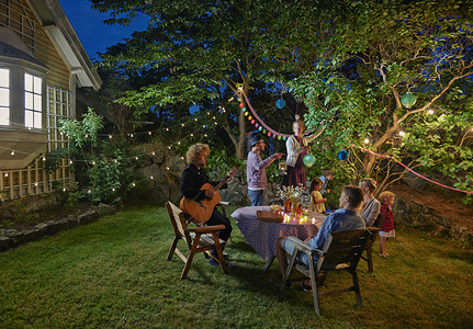 夜晚花园中举办家庭聚会的快乐一家人背景图片