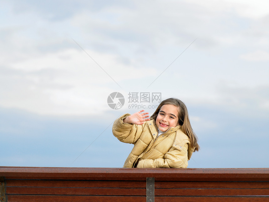 坐在长椅上挥手的女孩图片
