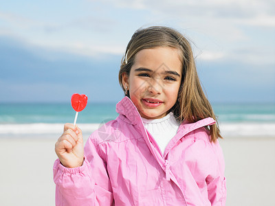 海边抱棒棒糖的小女孩图片
