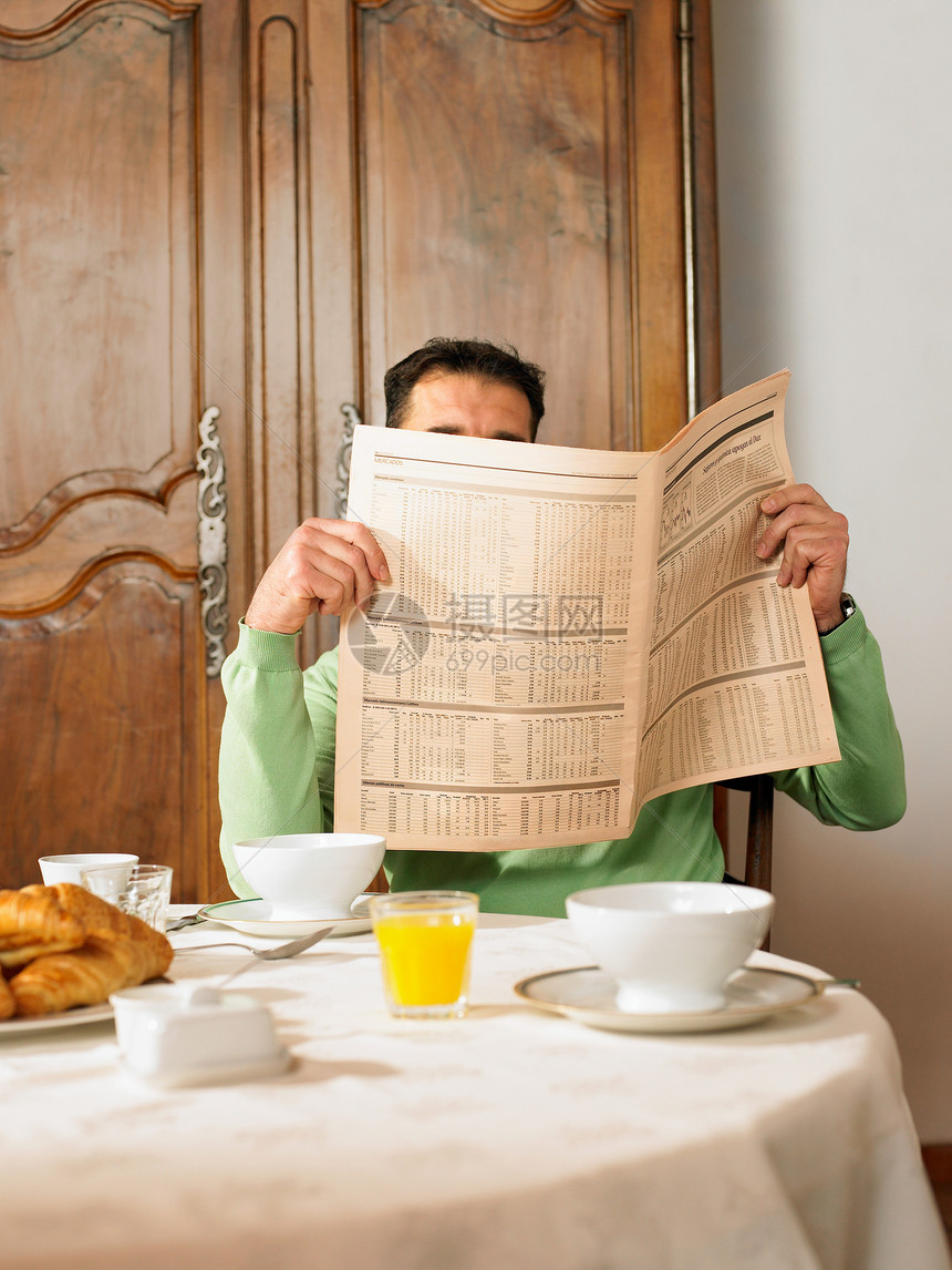 坐在早餐桌旁看书的男人图片