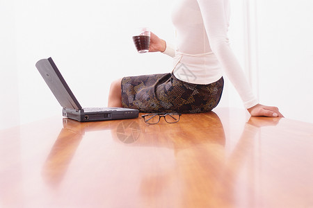 女人坐在桌上看笔记本电脑一个人高清图片素材