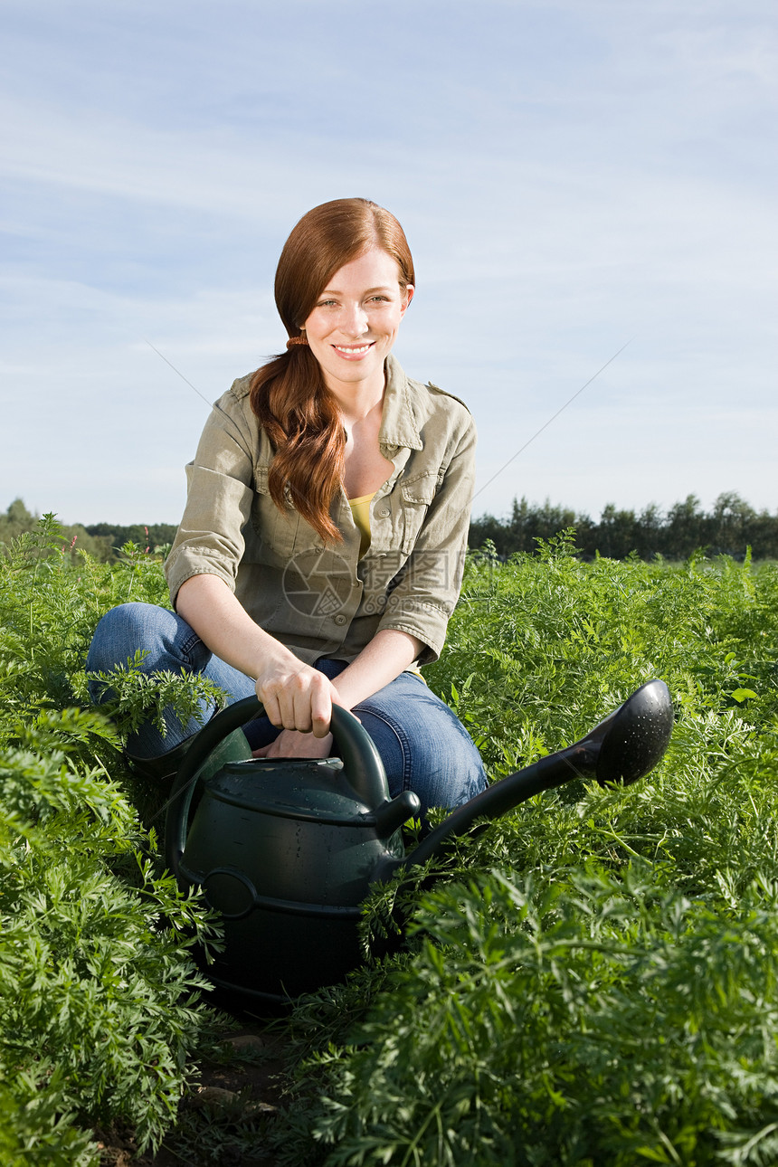 用水罐浇灌田里的庄稼的女人图片