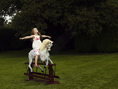 骑着摇摆木马的年轻女孩图片
