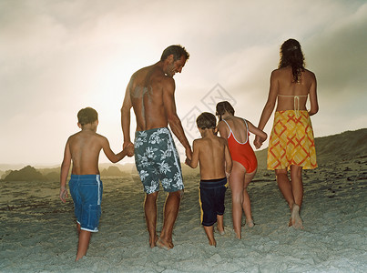 一家人牵着手在海滩上走开高清图片素材