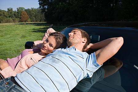 情侣在汽车引擎盖上放松图片