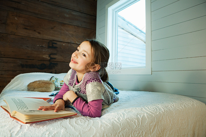 小女孩躺在床上看书图片