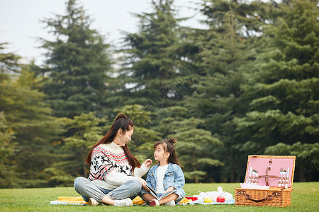 秋风季节食物温馨母女坐在草坪上读书背景