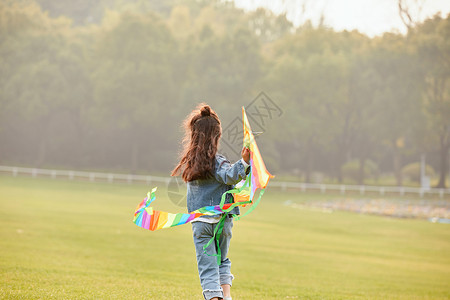 秋天孩子夕阳下小女孩草坪上放风筝背影背景