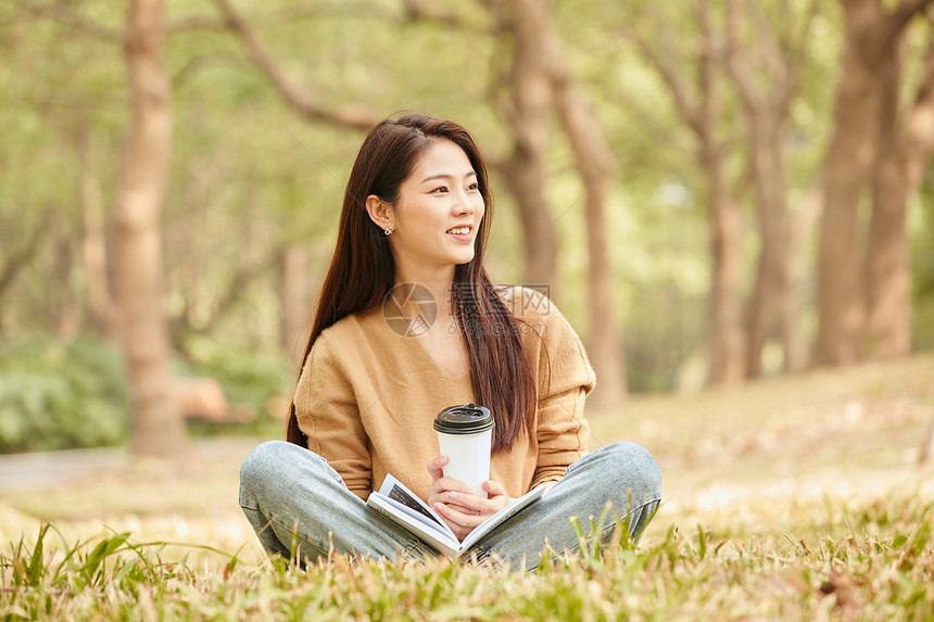 年轻女性草地上看书喝咖啡图片