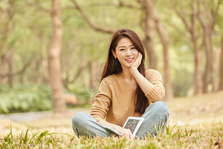 年轻女性坐在草地上看书图片