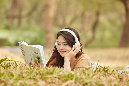 年轻女性户外听音乐看书高清图片