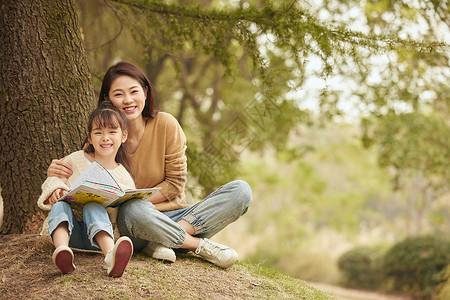 温馨母女坐在树下读书踏青高清图片素材