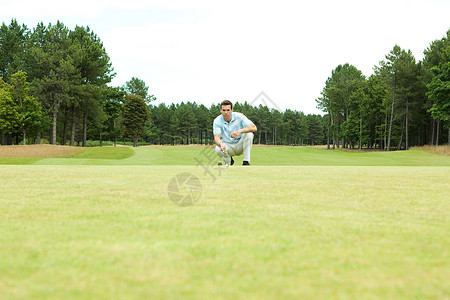 男高尔夫球手蹲在球道上图片