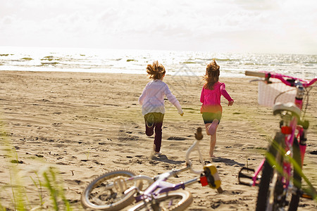 女孩们在海滩上奔向大海图片