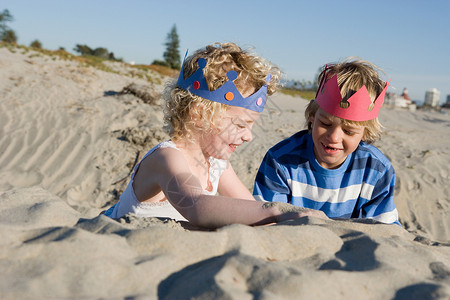 沙滩玩耍的女孩孩子们戴着纸冠在海滩上玩耍背景