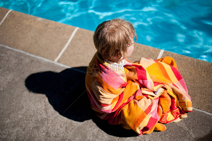 男孩裹着毛巾坐在池边图片