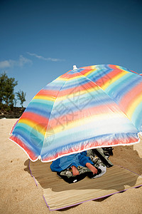 男孩躺在沙滩上的沙滩伞下图片