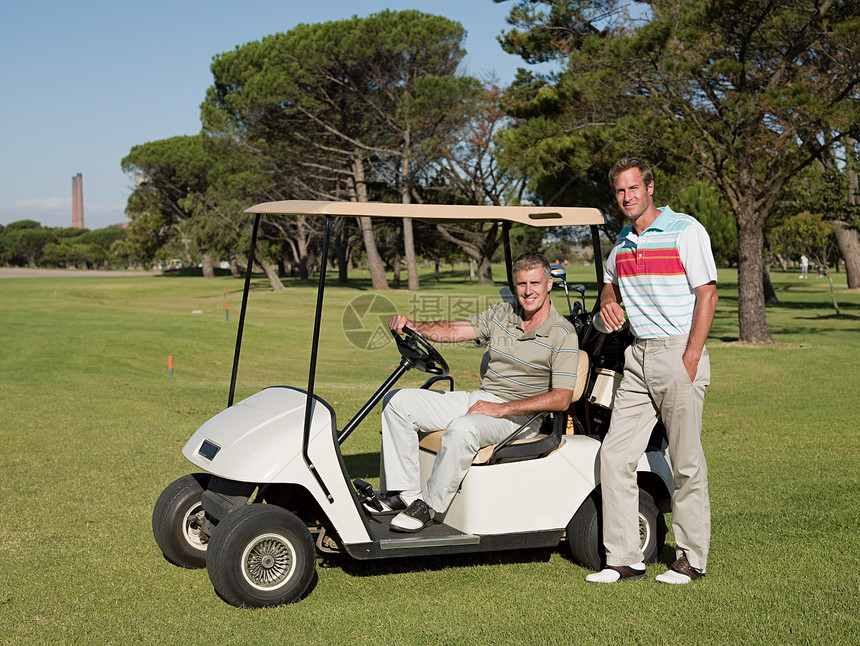 两个成熟的男子在高尔夫球场的高尔夫球车上图片