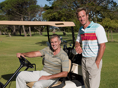 两个中年男子在高尔夫球场的高尔夫球车上图片