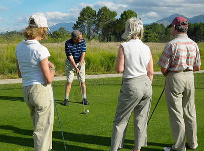 女人打高尔夫球中老年人在公园打高尔夫球背景