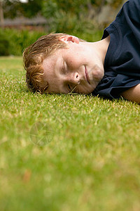 微笑的男孩躺在草地上图片