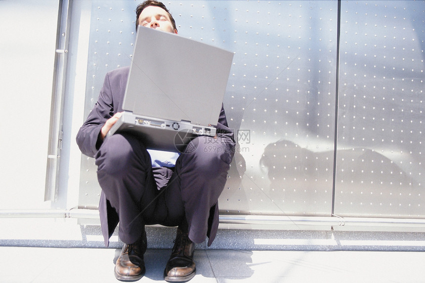 在阳光下坐着电脑的商人图片