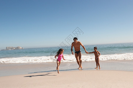 父亲和孩子们在海滩上奔跑图片素材