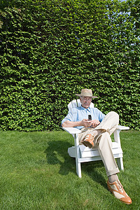 花园里带手机的老人看高清图片素材